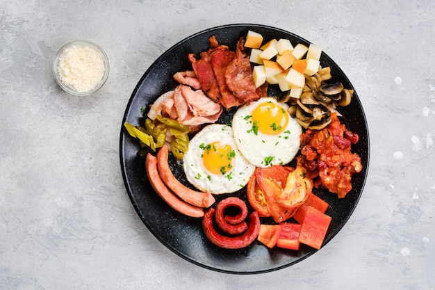 Assiette petit-déjeuner. egguf frit, saucisse, champignon, bacon, ragoût de haricots, jambon, cheddar, tomate et poivron