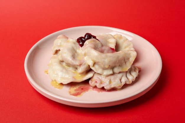 Assiette avec pierogi avec cerise sur fond rouge