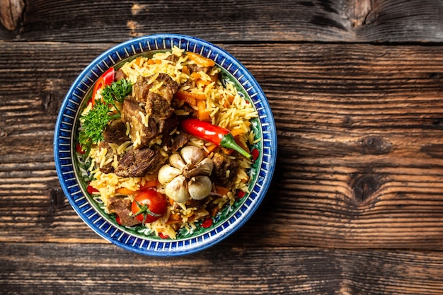 Assiette pilaf avec ornement oriental, fond en bois, concept de cuisine orientale ouzbek, vue de dessus, espace copie.