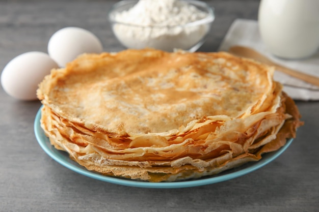 Assiette avec pile de délicieuses crêpes fines sur table