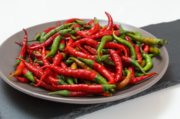 Assiette de piments forts frais et secs sur la planche à découper en pierre.