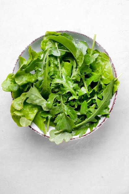 Assiette avec des plantes de roquette fraîches sur fond blanc Nourriture vue de dessus Plat végétarien sain