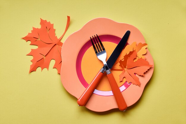 Assiette en plastique brillant sur papier jaune avec du papier Feuilles d'automne