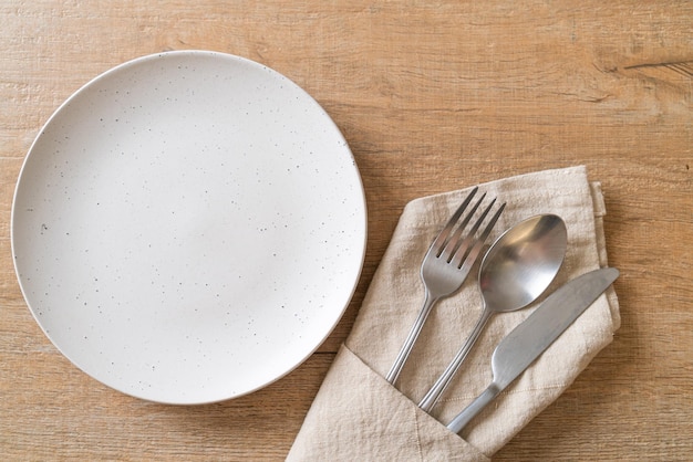 assiette ou plat vide avec couteau, fourchette et cuillère sur fond de carreaux de bois