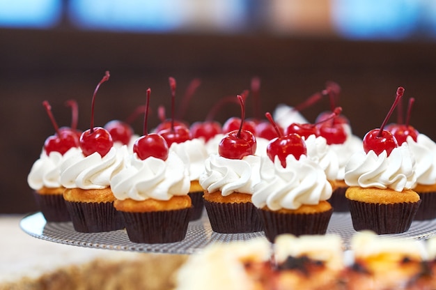 Assiette pleine de cupcakes avec crème et cerise sur le dessus