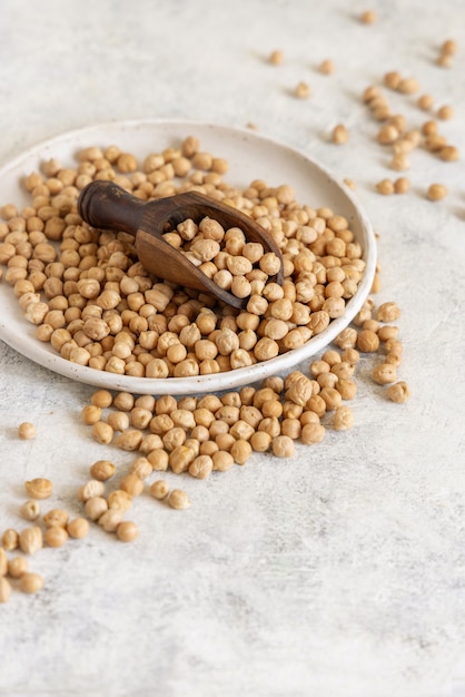 Assiette de pois chiches secs crus sur table blanche close up