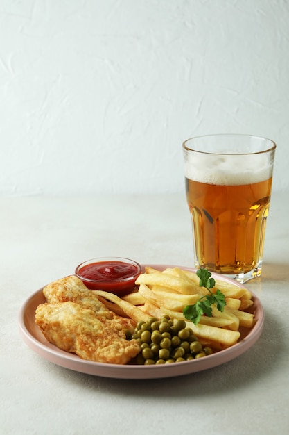 Assiette avec poisson frit et frites et bière isolée