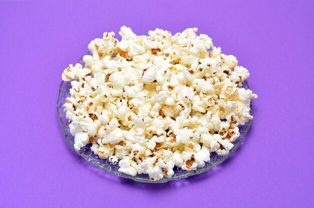 Une assiette de pop-corn sur fond violet close up