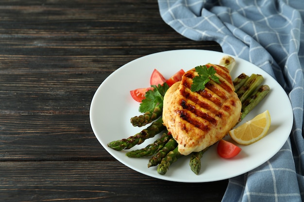 Photo assiette avec poulet grillé et ingrédient sur fond de bois