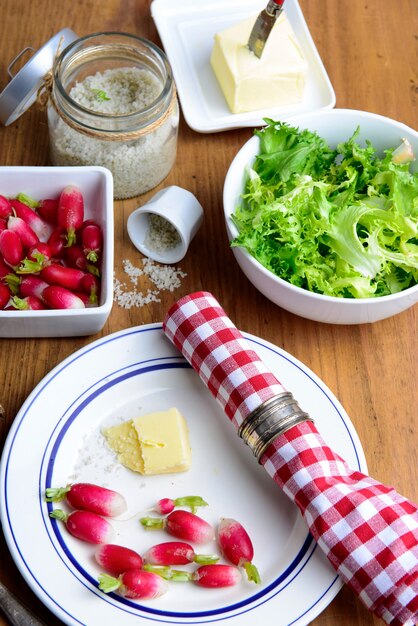 Assiette avec radis, beurre et salade sur une table rustique