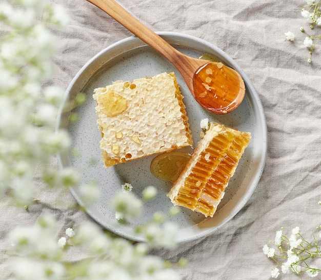 Assiette de rayons de miel frais sur fond de tissu de lin gris, vue de dessus