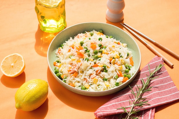 Une assiette de riz blanc avec des légumes sur un élégant mur orange tendance, la lumière du soleil, la nourriture asiatique