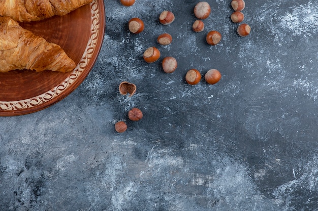 Une assiette ronde avec des croissants frais et des noix de macadamia saines.