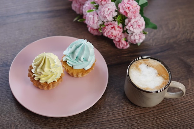 Une assiette rose avec trois petits gâteaux dessus à côté d'une tasse de café.