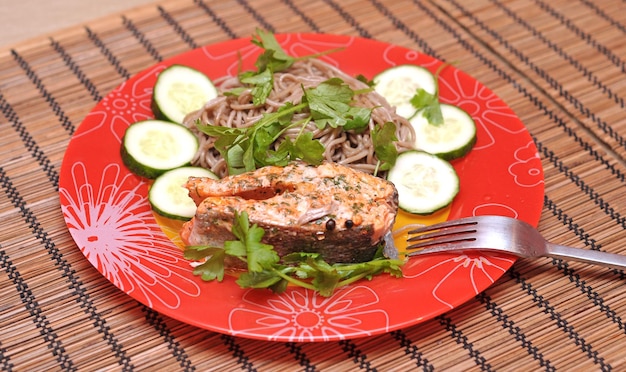 Une assiette rouge avec du saumon et des légumes dessus