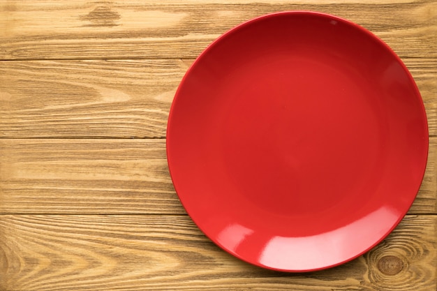 Assiette rouge vide sur une table en bois, vue de dessus