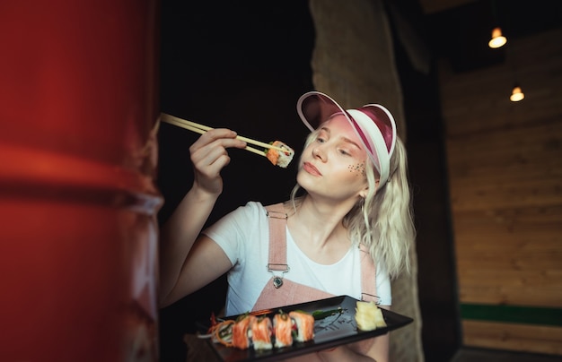 Assiette de rouleaux de sushi au restaurant avec femme tenant des baguettes