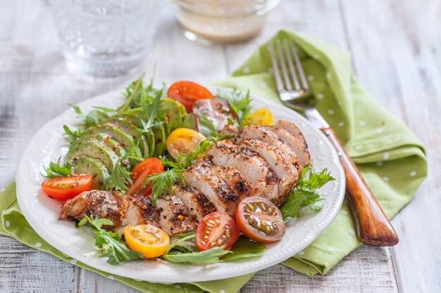 Assiette de salade aux tomates colorées, poitrine de poulet et avocat