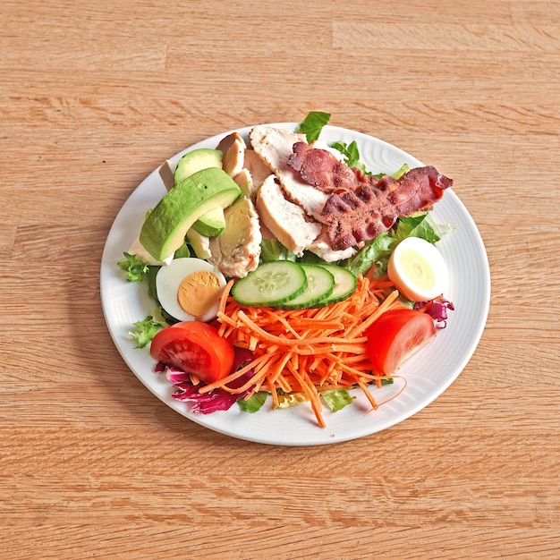 Assiette avec une salade d'avocat et de viande sur une table en bois