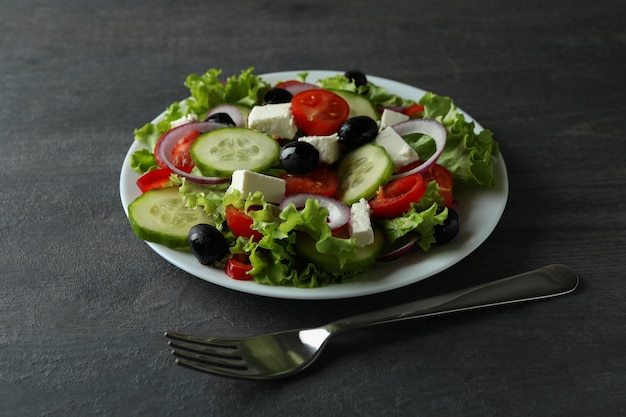 Assiette de salade grecque et fourchette sur une surface en bois sombre