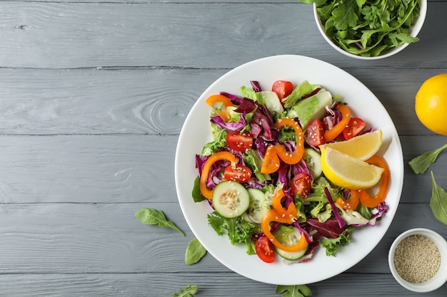 Assiette avec salade et ingrédients sur bois