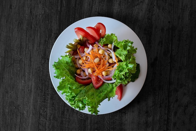 Une assiette de salade avec de la laitue, des tomates et des oignons.