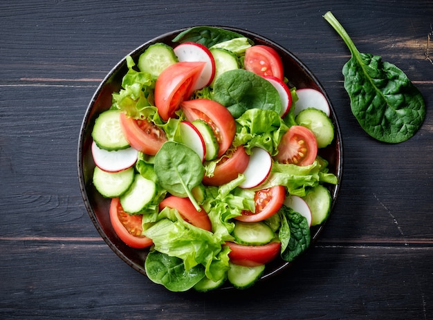 Assiette de salade de légumes frais sur table en bois foncé, vue de dessus