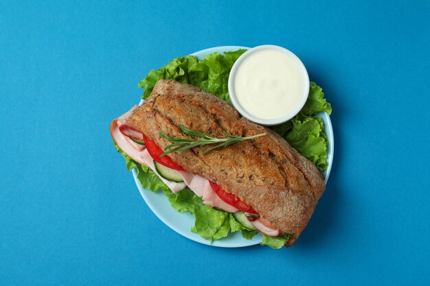 Assiette avec sandwich ciabatta sur fond bleu