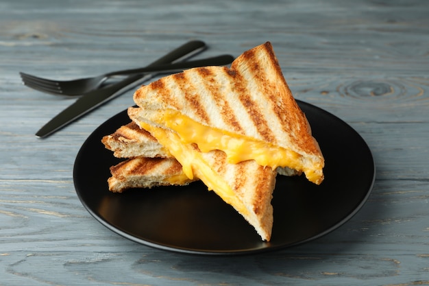 Assiette avec sandwichs grillés et couverts sur table en bois