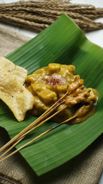Une assiette de satay indonésien avec sauce Padang sur une feuille de bananier dessus