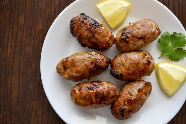 Une assiette de saucisses chypriotes sheftalia avec un quartier de citron sur le côté