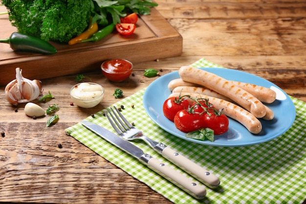 Assiette avec saucisses rôties et tomates sur fond de bois