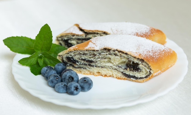 Sur l'assiette se trouve un gâteau aux graines de pavot myrtilles et feuilles de menthe