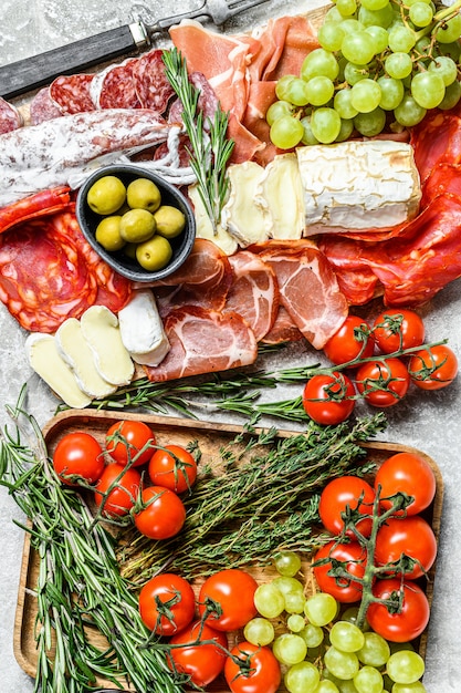 Assiette de service antipasti. Assiette de viande fumée à froid avec saucisse, jambon tranché, prosciutto, bacon, olives. Variété d'apéritif. Fond gris. Vue de dessus