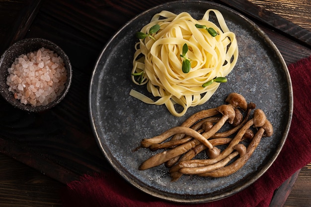 Assiette de shimeji et de nouilles cuites avec des champignons frits et des pâtes sur fond de bois