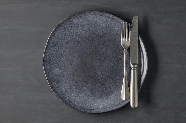 Assiette sombre sur fond de béton foncé avec couverts Modèle de démonstration de plat Vue de dessus avec espace de copie Mise à plat