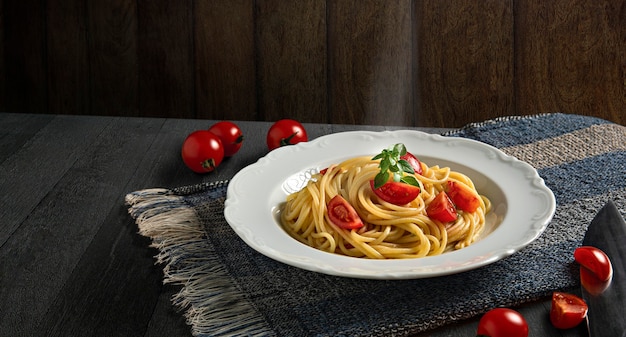 Assiette avec spaghetti, tomates et basilic sur fond de bois sombre. Spaghettis chauds à la vapeur. Espace de copie