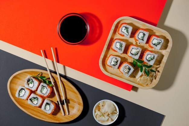 Une assiette de sushis et un verre de vin sont posés sur une table rouge.