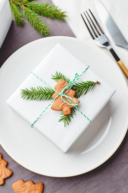 Assiette de table de fête de noël avec cadeau décoré de brins d'épinette et de pain d'épice