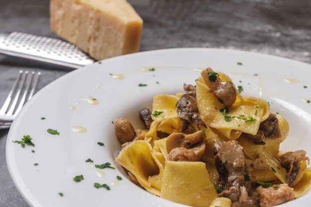 Photo une assiette de tagliatelle avec des champignons sur un marbre gris foncé