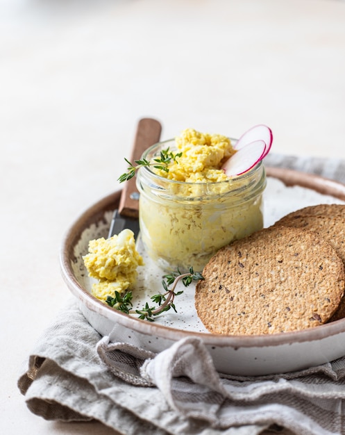 Assiette de tartelettes, crackers multigrains avec pâté aux œufs ou salade servie avec radis et thym.
