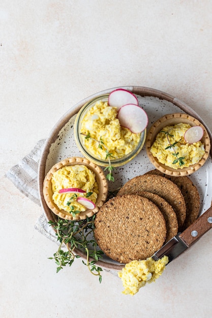 Assiette de tartelettes craquelins multigrains avec pâté aux œufs ou salade servie avec radis et thym