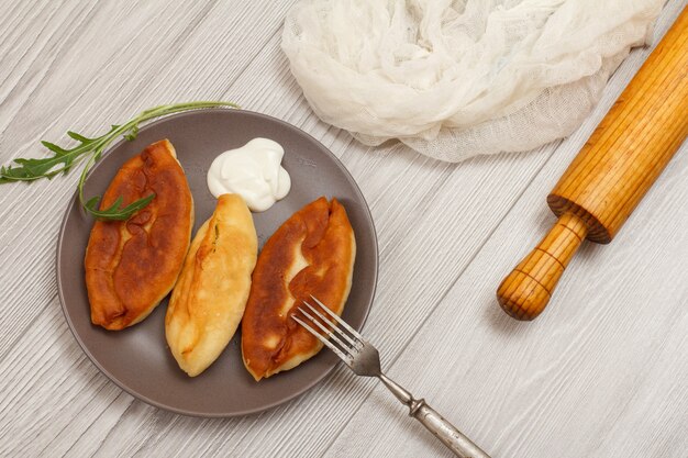 Assiette Avec Tartes Frites Et Fourchette En Métal, Rouleau à Pâtisserie En Bois Et Tissu Blanc Sur Des Planches En Bois. Vue De Dessus.