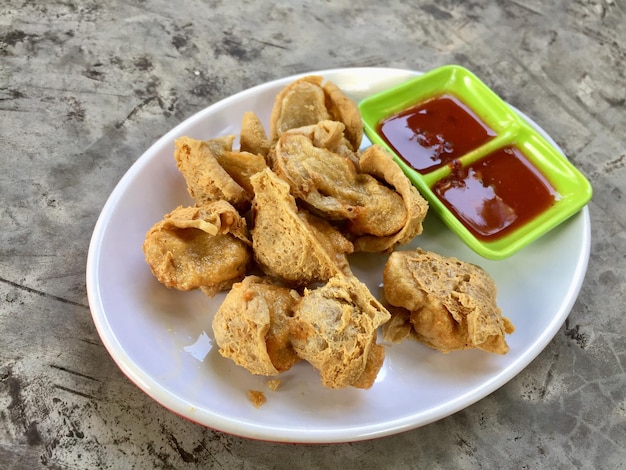 Une assiette de tofu frit avec sauce sur une assiette verte