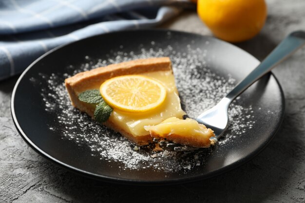 Assiette avec une tranche de tarte au citron sur fond gris avec une serviette et du citron, Close up