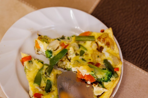 Assiette avec tranches d'omelette d'œufs brouillés aux légumes et spatule en acier inoxydable