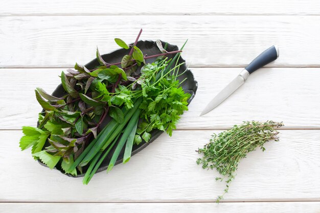 Assiette avec verdure fraîche et couteau sur blanc