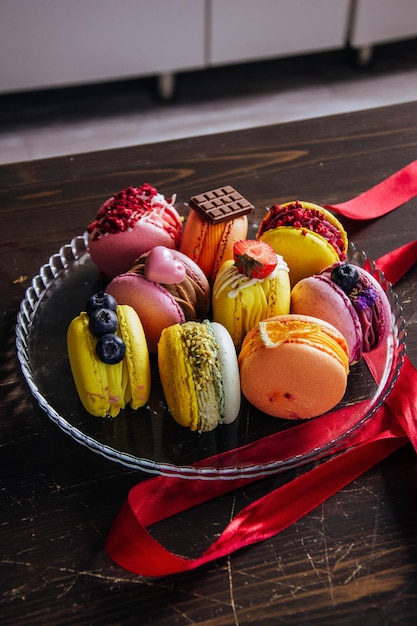 Photo une assiette en verre de macarons et de chocolats est posée sur une table en bois.