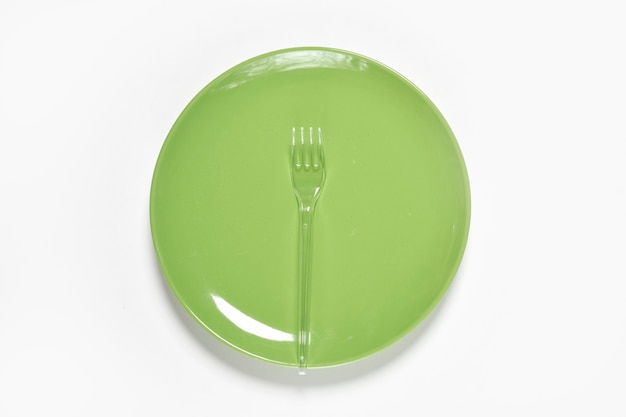 Assiette verte et fourchette en plastique avec cuillère sur fond vert copie espace
