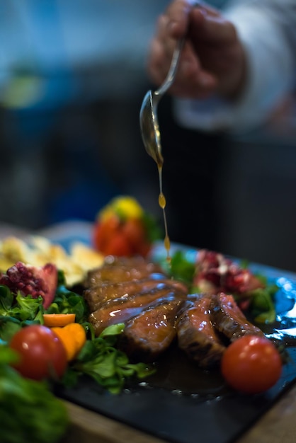 Assiette de viande de bifteck de finition à la main du chef avec vinaigrette Enfin et presque prête à servir à table